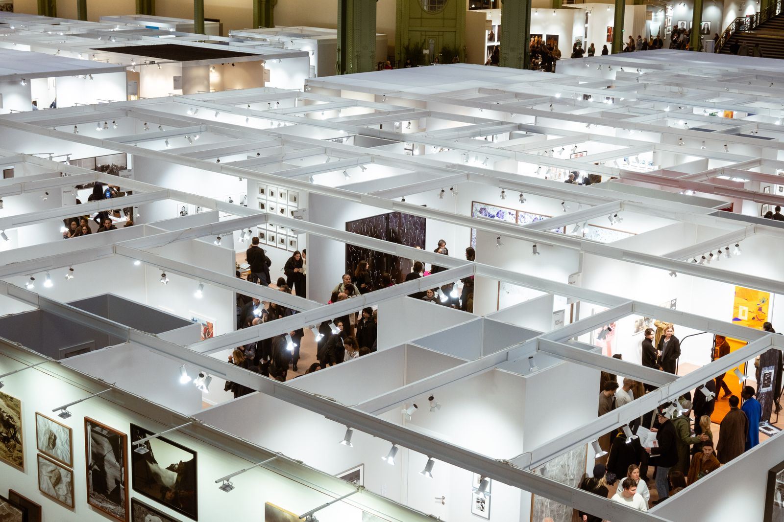 Vue plongeante sur des stands blancs et les visiteurs d'un salon parisien